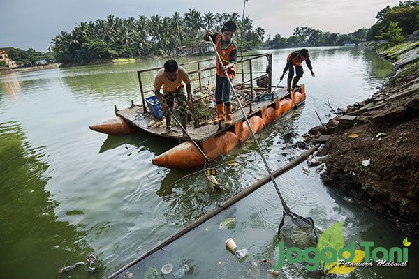 Para pekerja dinas lingkungan hidup DKI Jakarta sedang membersihkan sampah yang ada dipintu air Situ
