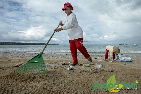 Dua pekerja sedang membersihkan sampah plastik yang terdampar dipantai Kedonganan, Bali.